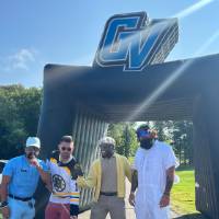 Four football alums standing in front of the GV inflatable.